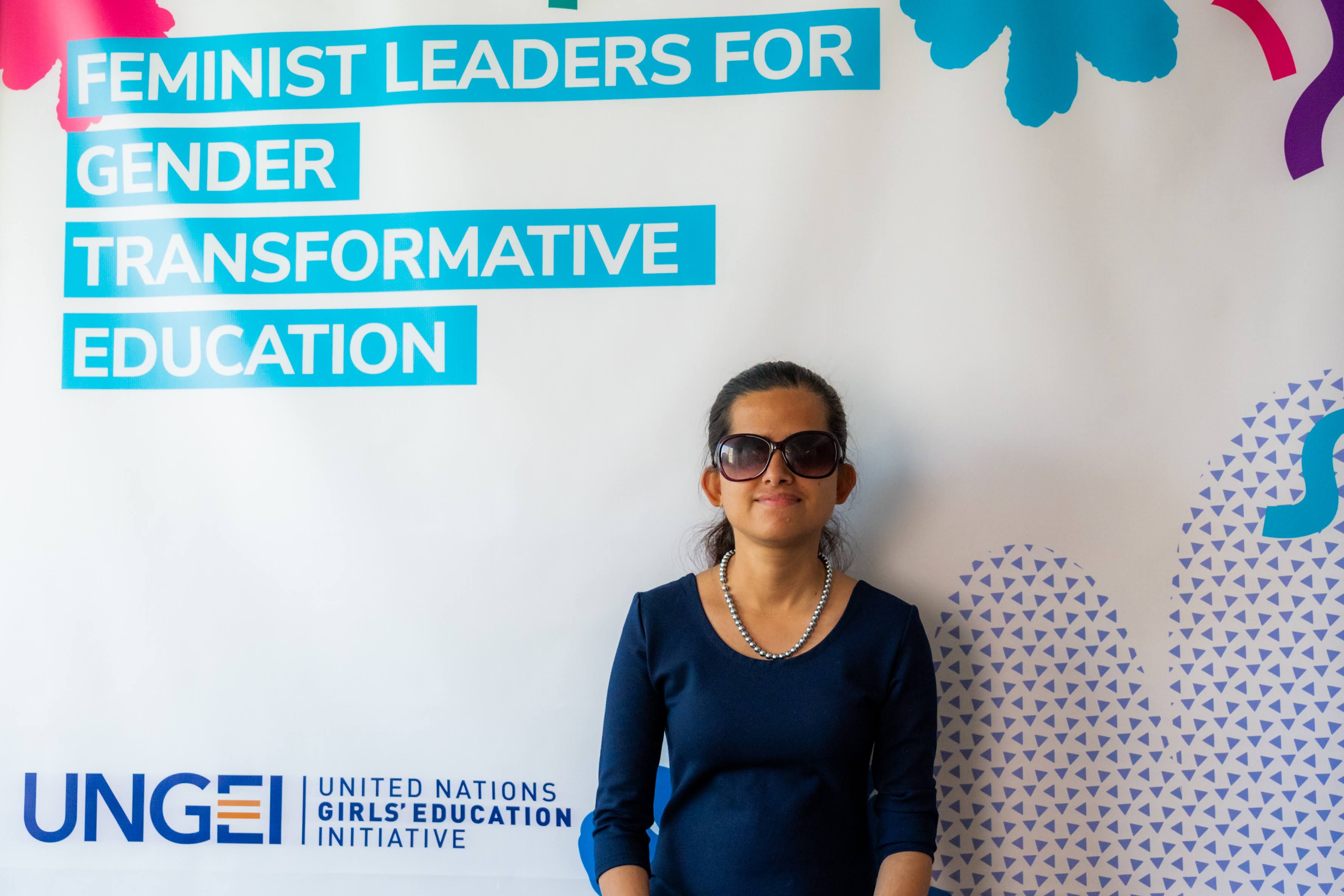 Laxmi in front of a backdrop that says Feminist Leaders for Gender Transformative Education
